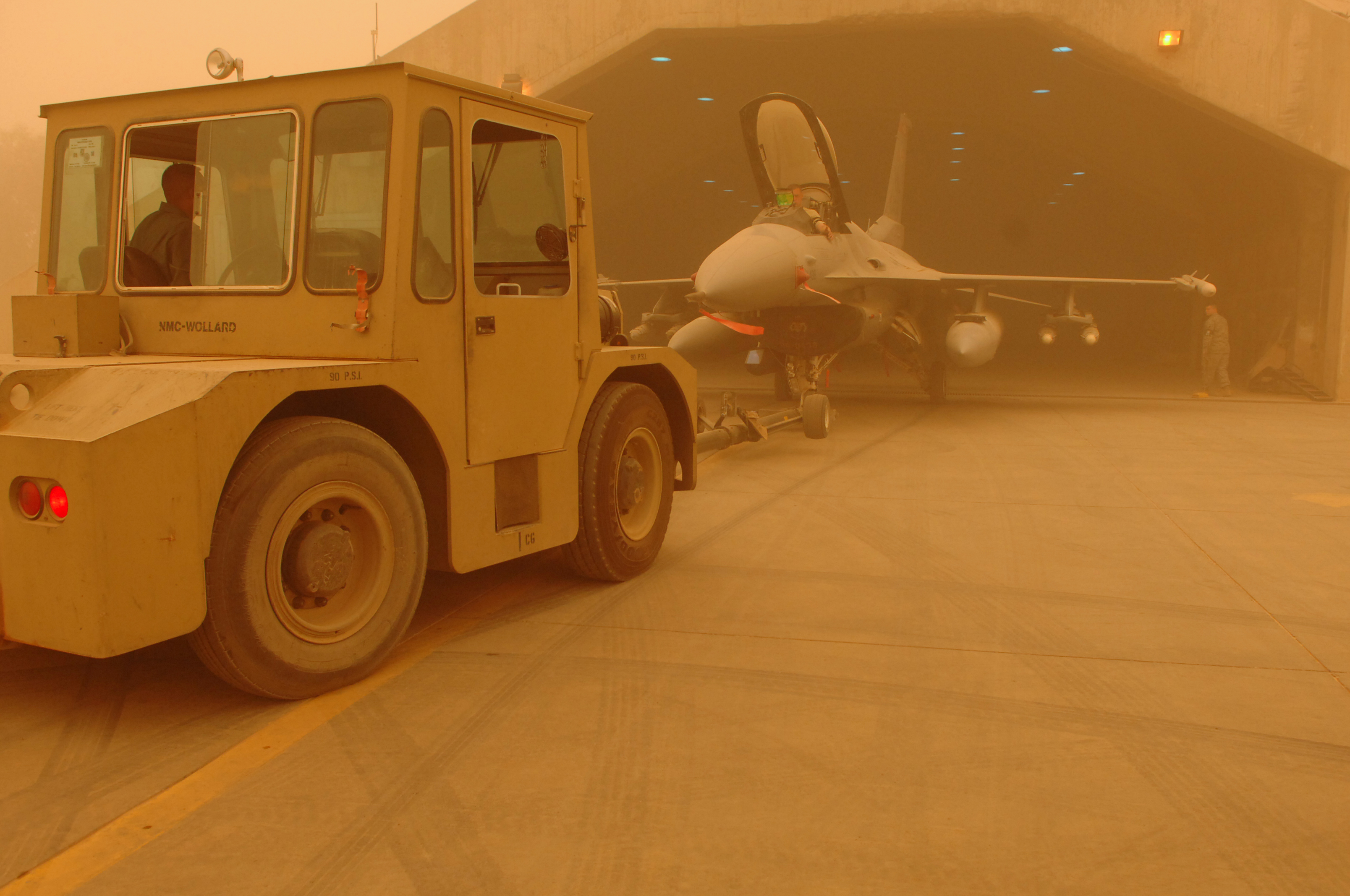 Tugging an F-16 into a shelter during a dust storm